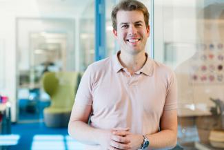 Blond man smiling leaning against a glass door