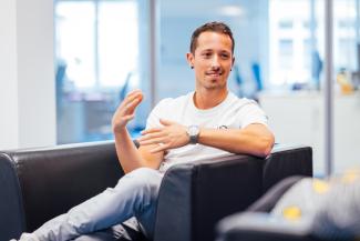 young man sitting in a chair, gesture with his hands