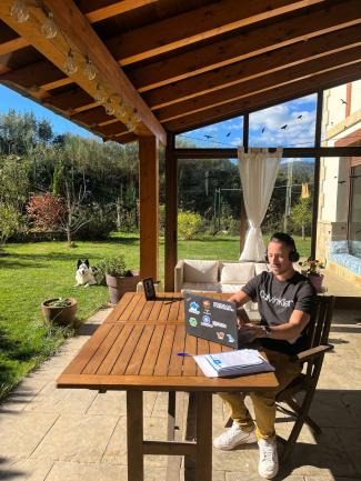 young man sitting in front of a laptop on a sunny terrace