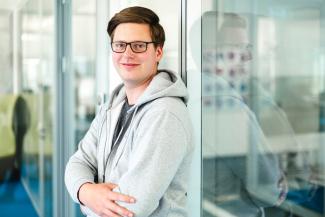 young man with glasses leaning to a glass door