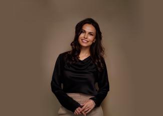 woman with dark hair smiling, brown background